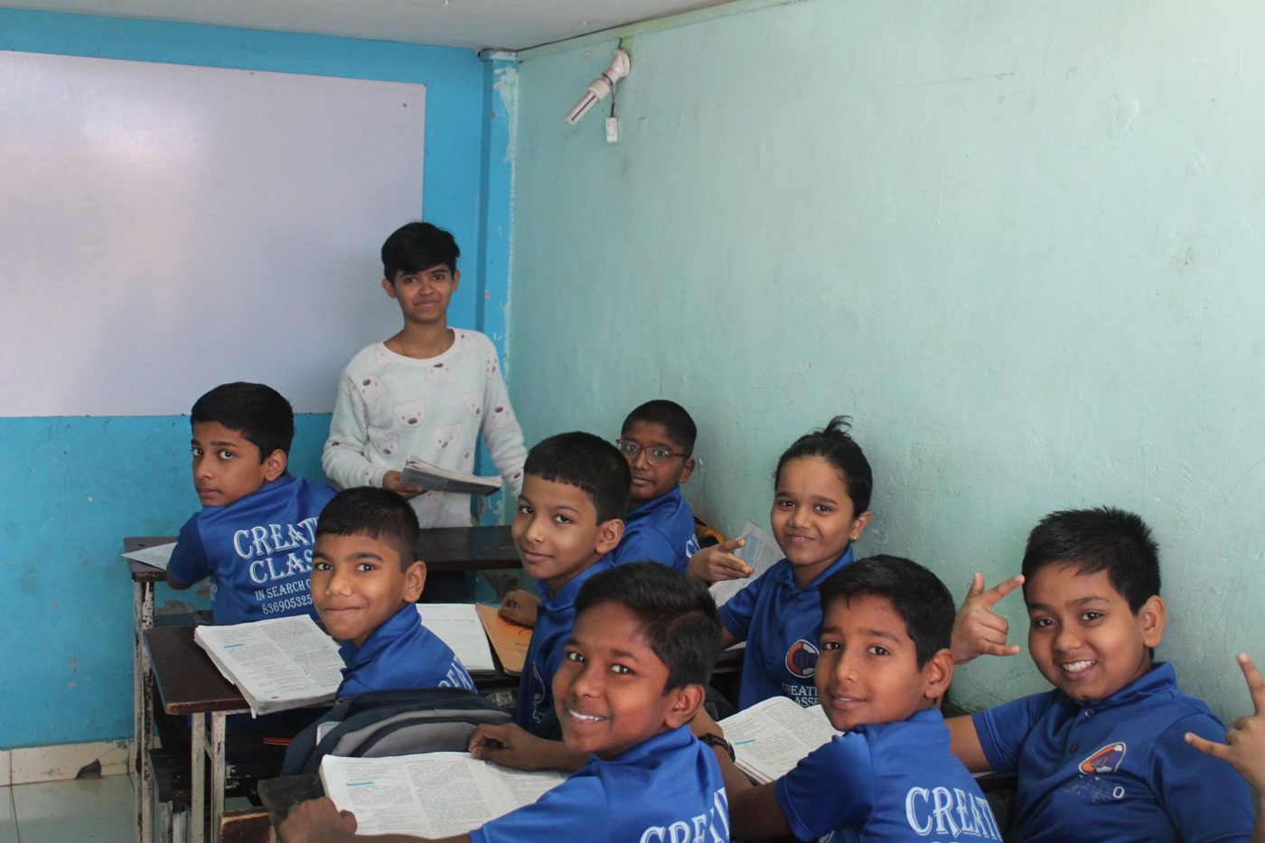 Creativo Classes students in their blue class T-shirts, smiling together in the classroom